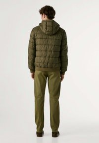 Olivgrön puffjacka med huva, med quiltad textur och ribbade manschetter, i kombination med matchande avslappnade byxor.