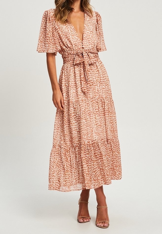 Maximekränning i persikofärgad tyg med en subtil tryck, med en djup V-ringning, korta fladdrande ärmar och ett knytliv. Tierskurt design.