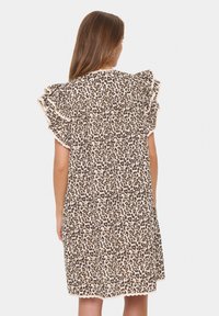 Leopardenmuster-Kleid mit Rüschensäumen, beigem Grund, dunkelbraunen Flecken und gewelltem Saum. Leichter Stoff, lockere Passform.