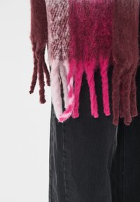 Strikket tørklæde med en gradient af burgunder, pink og lyserøde nuancer; har frynsede ender; præsenteret mod sort stof.