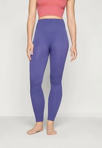 Ribbet lilla leggings med høy midje, tettsittende fasong og en jevn tekstur, kombinert med en rosa crop-top.