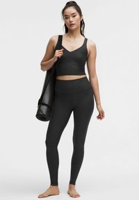 Zwart workoutset met een aansluitende cropped top met een V-hals en leggings met een subtiel luipaardpatroon, gemaakt van rekbaar, textuurmateriaal.