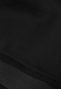 Zbliżenie na czarny materiał z teksturowaną powierzchnią. Krawędzie prezentują uporządkowany, płaski szew z lekko podniesioną krawędzią dla zwiększenia trwałości.