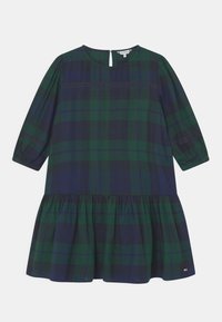 Zelené a námořnické kostkované šaty s kulatým výstřihem, tříčtvrtečními rukávy a rozšířeným volánkovým lemem. Obsahují klíčovou otvor vzadu.