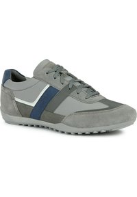 Zapatilla atlética gris que presenta una combinación de materiales lisos y texturizados, con acentos en azul y gris oscuro, y una suela de goma con pequeños tapones.