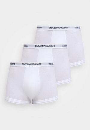 Trois boxers Emporio Armani blancs empilés, chacun avec une ceinture élastique de marque et une poche avant contournée.