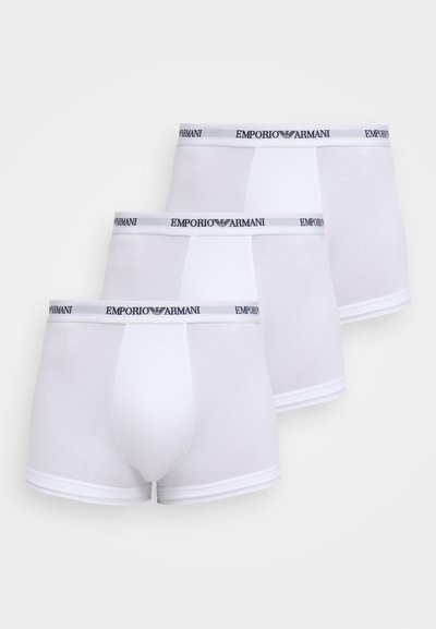 Trois boxers Emporio Armani blancs empilés, chacun avec une ceinture élastique de marque et une poche avant contournée.