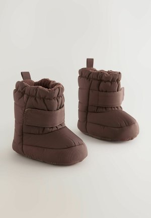 Bottes rembourrées brunes avec un intérieur doux, présentant un design cousu, une sangle à boucle et un bout arrondi. Convient pour les temps froids.