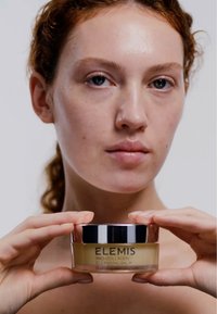 Barattolo dorato di ELEMIS Pro-Collagen Cleansing Balm con coperchio argentato. Etichetta trasparente che mostra il nome del prodotto e i dettagli.