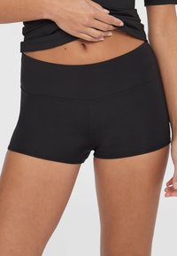 Svart aktive shorts med høy midje, laget av elastisk stoff. Har en glatt tekstur og minimale sømdetaljer.