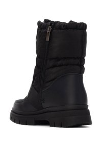Botas de tobillo aisladas negras que cuentan con una parte superior de nylon acolchado, cierre lateral con cremallera, suela de goma texturizada y panel lateral elástico para mayor flexibilidad.