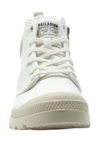 Sneaker bianco alto con tomaia in tela, suola in gomma e cuciture prominenti. Presenta materiali riciclabili e un'etichetta con il marchio sulla linguetta.