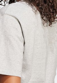 Grå bomullströja med klassisk passform, korta ärmar och en mjuk textur, med synliga sömdetaljer vid axlar och sidor.