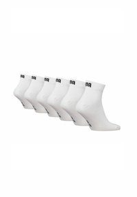 Six pairs of white ankle socks with black brand logo on ribbed cuffs, arranged in a diagonal row against a white background.