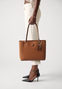 Borsa tote sintetica marrone con doppi manici, bordi neri a contrasto e accessori in metallo argentato con logo e dettaglio portachiavi.