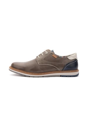 Zapato informal de hombre con cordones en ante topo con puntera perforada, tacón en contraste azul marino y crema, y suela blanca con ribete marrón.