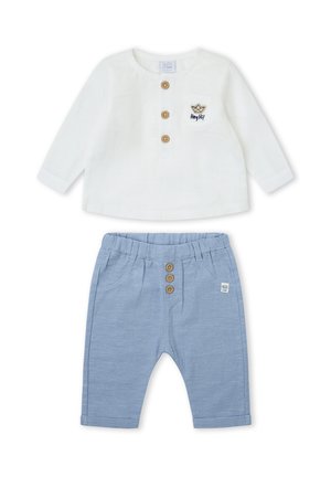 Camiseta blanca de manga larga para bebé con botones de madera y bolsillo, combinada con pantalones a rayas azul claro con botones de madera.