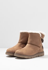 Brązowe zamszowe botki za kostkę z białym sztucznym futrem, okrągłym czubkiem, dekoracyjnym zapięciem oraz teksturowaną gumową podeszwą.