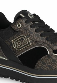 Baskets à motifs noirs et marron avec une tige texturée, un logo métallique, une fermeture à lacets et une semelle épaisse et sculptée avec des accents subtils.