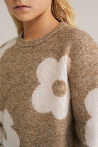 Brown and cream sweater with large floral patterns. Made of soft knit material, features a round neckline and textured fabric.