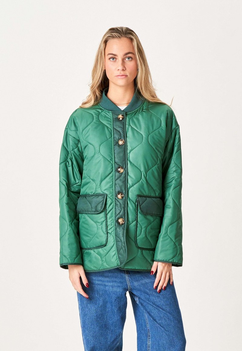 Grøn quilted jakke lavet af skinnende materiale, med krave, guldknapper og to frontlommer med kontrasterende teal accenter.