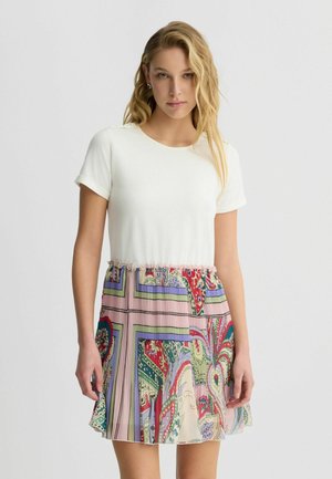 Top bianco a maniche corte, vita arricciata e gonna a pieghe con fantasia in colori pastello, caratterizzata da motivi floreali e geometrici.