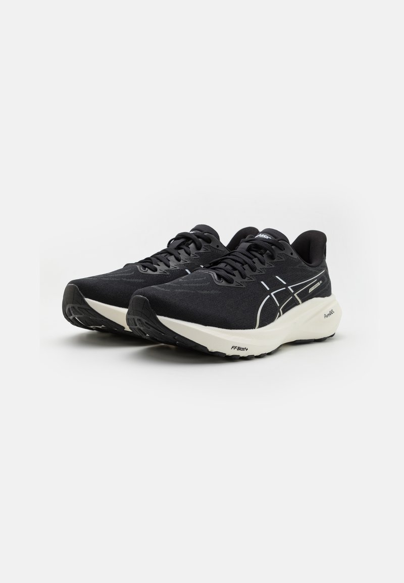 Zapatillas de correr negras con parte superior texturada, que presentan acentos blancos, puntera redonda y mediasuela blanca acolchada, ideales para uso atlético.