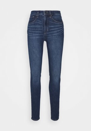 Dark blue skinny jeans with high waist, front and back pockets, and slight whiskering detail on thighs.