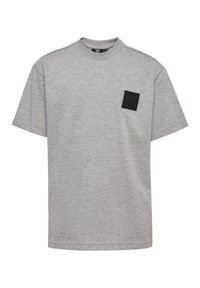 Grå bomulds T-shirt med rund hals, korte ærmer og et firkantet sort mærke med et logo på venstre side af brystet.