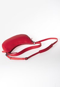 Rode leren schoudertas met een slanke vorm, een ritsluiting en een verstelbare strap. Soepele textuur met minimale detailing.