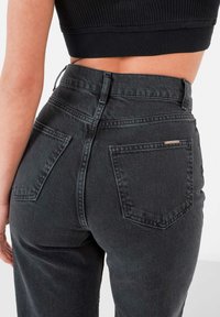 High-waisted, zwarte denim jeans met een klassieke vijf-pocketontwerp, stevige stiksels en een licht vervaagde textuur.