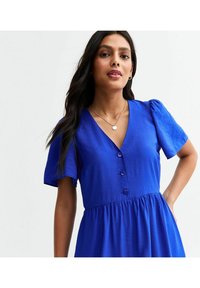 Vestido azul con mangas cortas abullonadas, escote en V, botones decorativos en la parte delantera y detalle de cintura fruncida. Textura de tela suave.