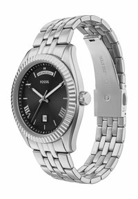Montre en acier inoxydable argenté avec un cadran noir, marqueurs horaires en chiffres romains, fenêtre de date et lunette striée. Design de bracelet à maillons.