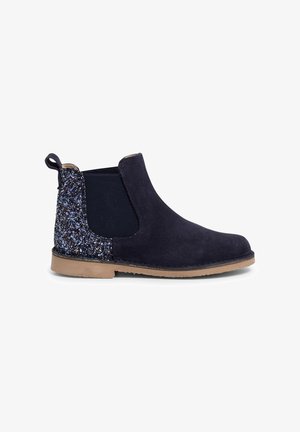Bottines Chelsea en suède bleu marine avec des côtés élastiques, des accents scintillants bleu et argent sur le talon, et une semelle en caoutchouc beige.