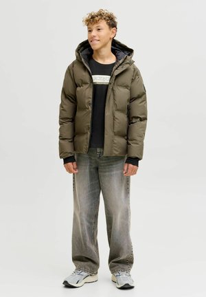 Olivengrøn pufferjakke med hætte, sort t-shirt under, lysegrå vide jeans og grå sneakers med sorte detaljer.