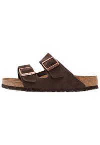 Sandales en daim marron avec deux brides réglables, boucles en métal cuivre, semelle en liège et semelle extérieure en caoutchouc texturé.