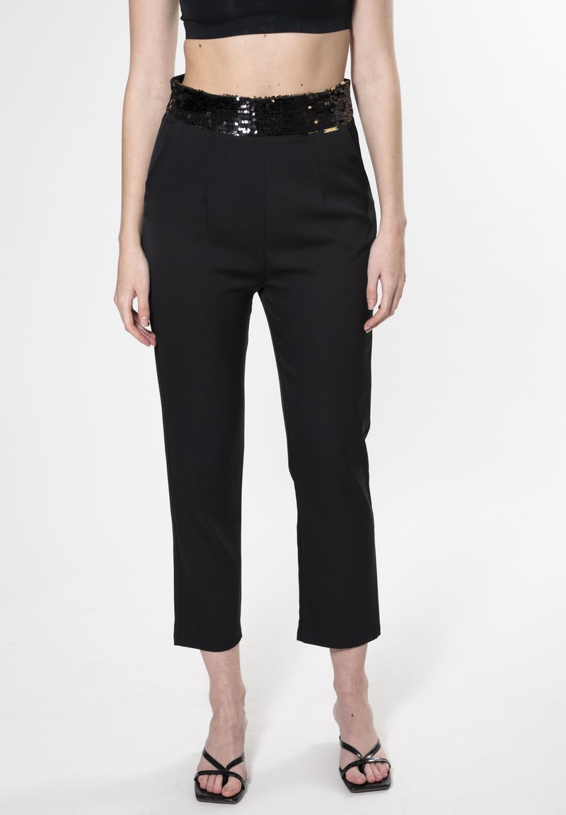 Zwarte high-waisted broeken met een glanzende zwarte pailletten tailleband, getailleerde pasvorm, verkorte lengte en een gladde textuur. Gecombineerd met zwarte sandalen.