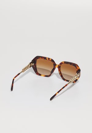 Tortoiseshell sunglasses with an octagonal frame, gradient brown lenses, and gold chain-accented temples. Smooth plastic texture.