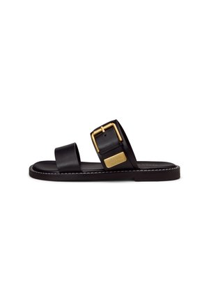 Zwarte platte slipper met twee brede riemen, een gouden gesp op de bovenste riem en witte stiksels langs de rand van de zool.