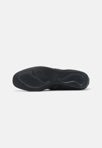 Suola di scarpa nera con gomma testurizzata per una presa ottimale, caratterizzata da un motivo ondulato e un logo del marchio, progettata per durabilità e trazione.