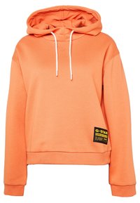 Oranžová mikina s kapucí z měkké tkaniny, vybavená šňůrkou na kapuci, žebrovanými manžetami a značkovou nášivkou s černými a žlutými akcenty.