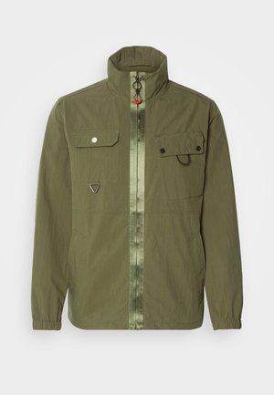 Olive green jacket with a stand collar, front zipper, two chest pockets, and elastic cuffs. Features a tonal center stripe and metal hardware.