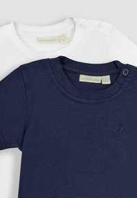 Du šortai su trumpomis rankovėmis, vienas tamsiai mėlynas, kitas baltas. Minkštas medvilnės audinys, apvalus kaklas, patentukai ant peties, mažas burlaivio logotipas ant tamsiai mėlynos marškinės.