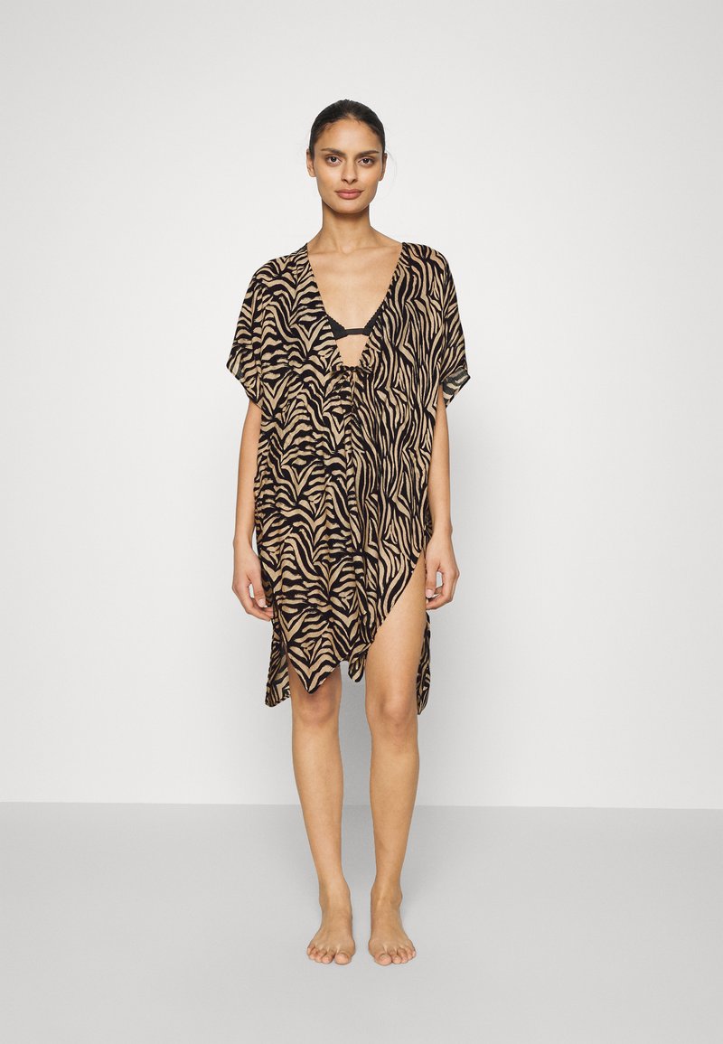 Copricostume in stampa animale nei toni del beige e nero, con scollatura a V profonda, maniche corte e orlo asimmetrico. Tessuto leggero con un design fluido.