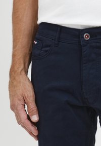 Pantalons en coton bleu marine avec une poche avant ornée d'un détail en rayures rouge, blanc et bleu, une fermeture à bouton et une coupe droite.