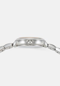 Side view of a silver metal wristwatch with a rounded button crown and linked bracelet on a white background.