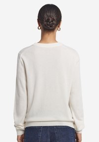 Cremfarbener Pullover mit langen Ärmeln, gerippten Bündchen und lässiger Passform. Sanfte Textur, Rundhalsausschnitt und minimalistische Nahtdetails an den Schultern.