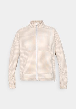 Beige och vit rutig zip-jacka med hög krage, långa ärmar, elastiska manschetter och framfickor på en enfärgad bakgrund.