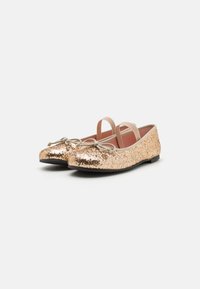 Bailarinas brillantes doradas con punta redondeada y dos correas elásticas. Presentan una superficie de lentejuelas texturizadas y una suela plana negra.
