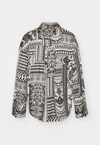 Black and white patterned shirt featuring various geometric and floral designs, a collar, and long sleeves. Smooth fabric texture.